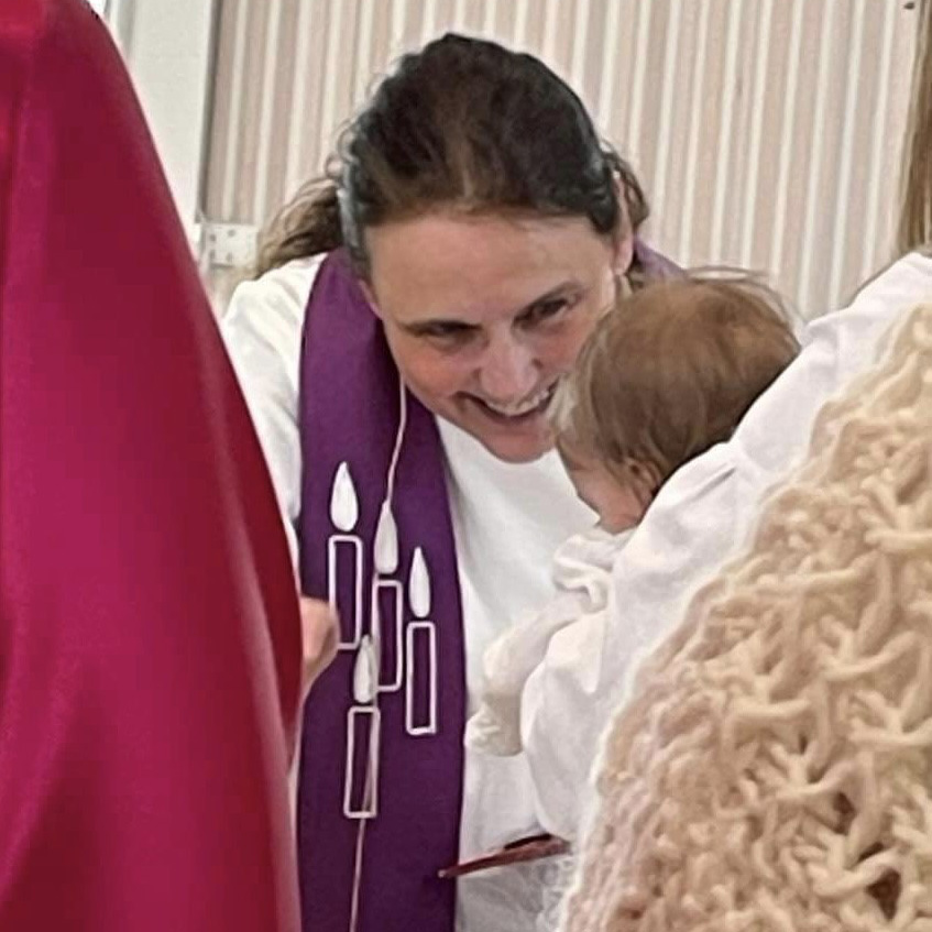 En prest som døper et barn i Eiksmarka kirke